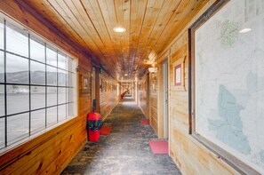 A long hallway with wooden walls and a carpeted floor, leading to a large window with a view of a snowy landscape. - Livingston Inn - Historic (Livingston)