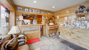 A wooden interior with a reception desk, a couch, and a fireplace. - Livingston Inn - Historic (Livingston)