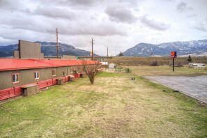 A building with a red roof, a small adjacent structure, and a parking area with a sign indicating a gas station.