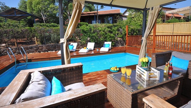 A poolside area with lounge chairs, a bar, and a view of the pool. - The Golan Cabin (Had Nes)