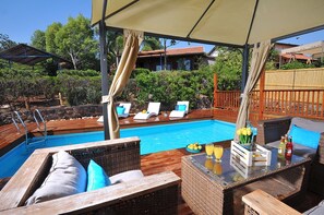 Un área junto a la piscina con sillones de descanso, un bar y vistas a la piscina.
