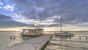 Een steiger met een houten hutje en een zeilboot.