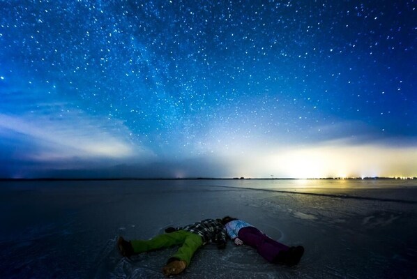 A person lying on a frozen surface under a starry sky.