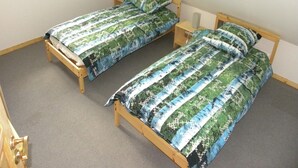 Ein Zimmer mit zwei Holzbetten, jeweils mit einem gemusterten Überwurf und Kissen.