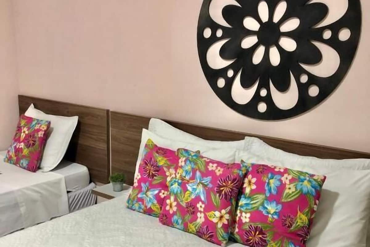 Habitación de hotel con una cama grande, dos almohadas con estampado floral, un adorno redondo en la pared y un cabecero.