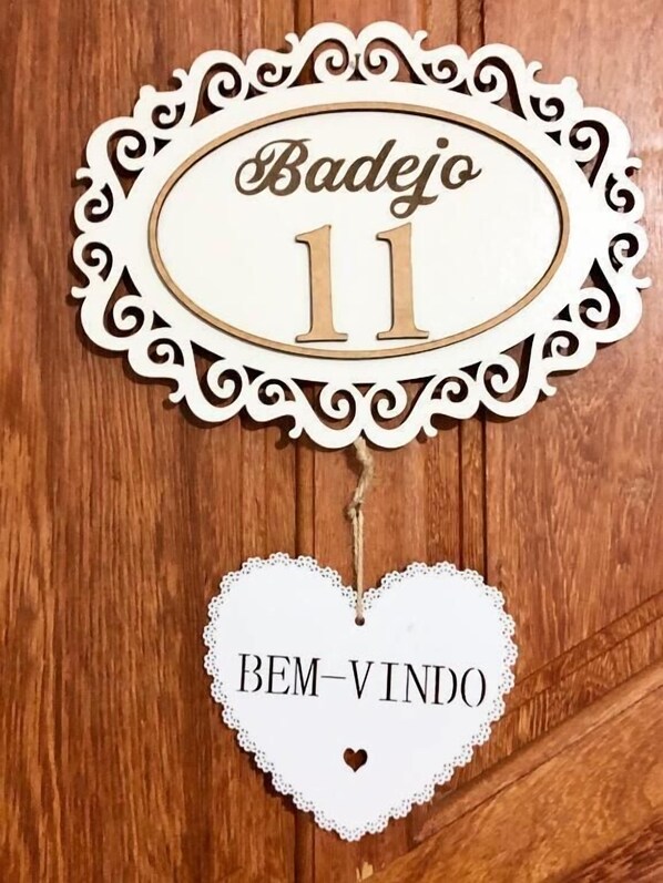 A decorative sign with the name "Badejo" and the number "11" on a wooden background. - Pousada do Pescador (Penha)