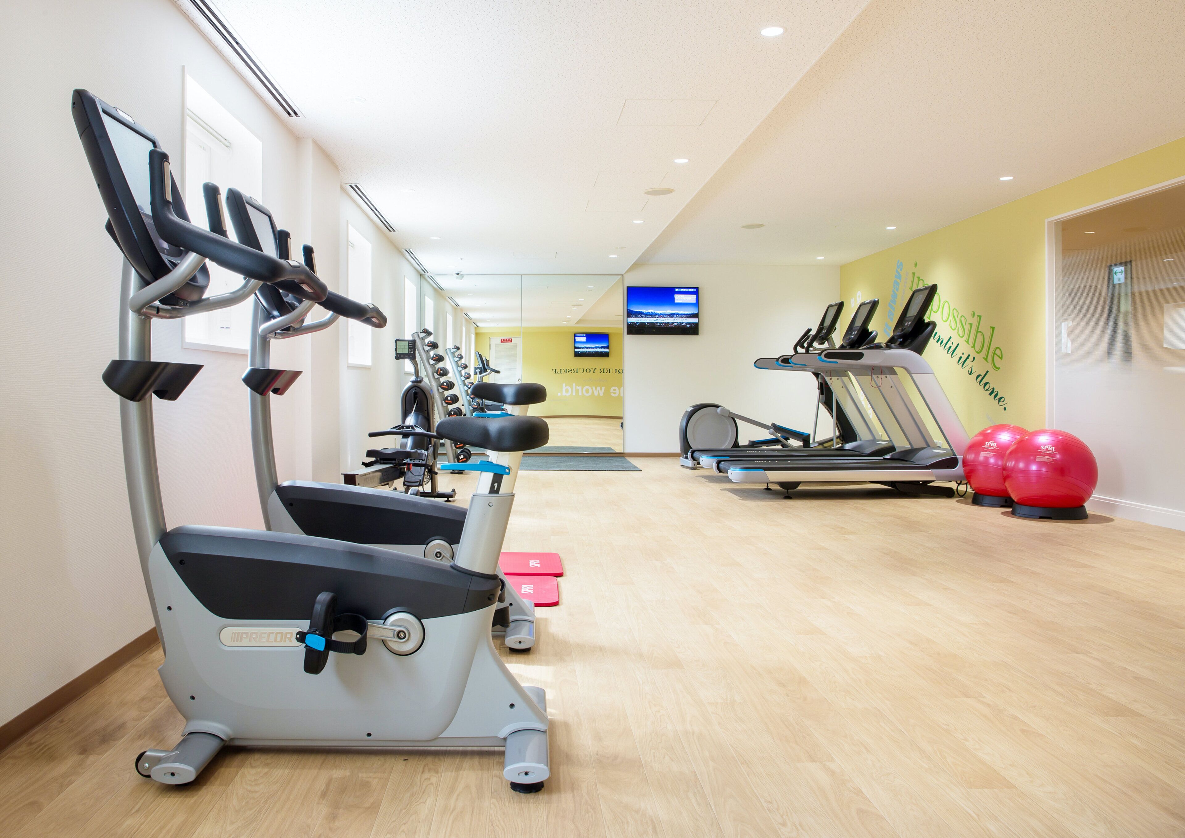 A gym with treadmills, elliptical machines, and exercise balls.