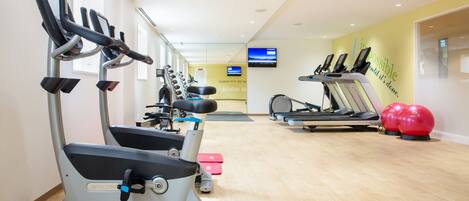 A gym with treadmills, elliptical machines, and exercise balls.