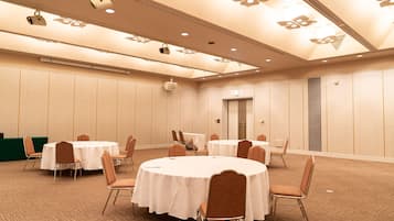 A conference room with round tables and chairs, a green counter, and a door.
