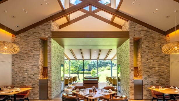 A spacious dining area with high ceilings and natural light, featuring a modern design with exposed beams and stone walls. - Holiday Inn Resort Kuroyon by IHG (Omachi)
