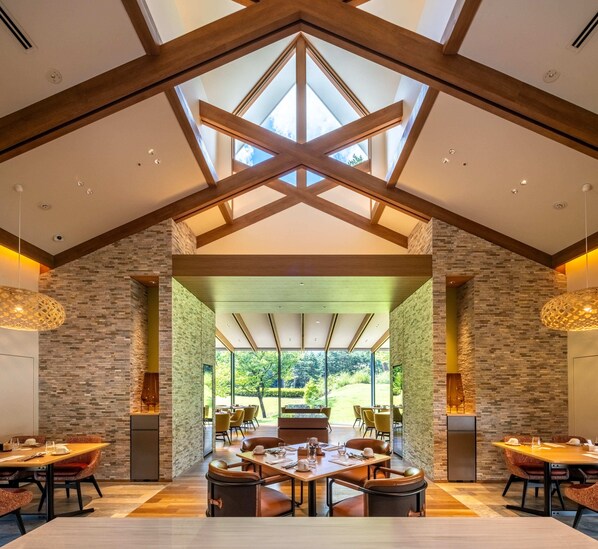 A spacious dining area with high ceilings and natural light, featuring a modern design with exposed beams and stone walls. - Holiday Inn Resort Kuroyon by IHG (Omachi)