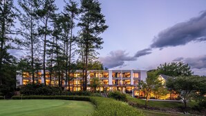 A modern hotel with multiple floors, surrounded by a well-maintained garden and tall trees. - Holiday Inn Resort Kuroyon by IHG (Omachi)