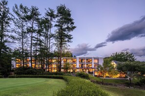 A modern hotel with multiple floors, surrounded by a well-maintained garden and tall trees. - Holiday Inn Resort Kuroyon by IHG (Omachi)
