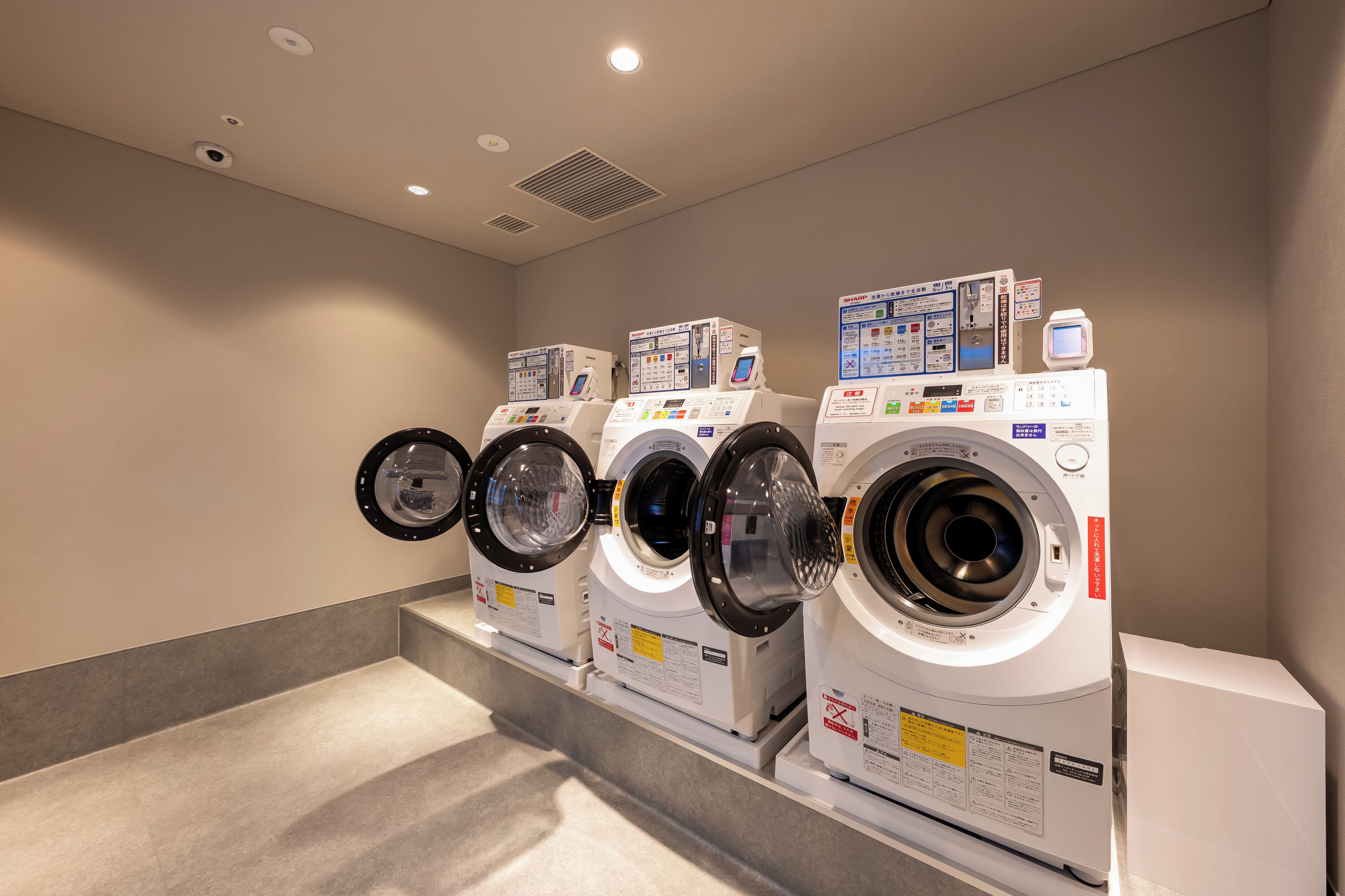 A row of front-loading washing machines in a commercial setting.