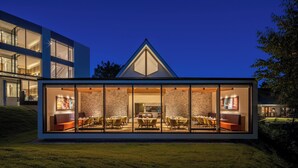 A modern house with a dining area visible through large glass windows, a stone exterior, and a well-lit interior. - Holiday Inn Resort Kuroyon by IHG (Omachi)