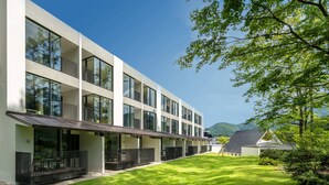 A modern multi-story building with large windows, a flat roof, and a well-maintained lawn. - Holiday Inn Resort Kuroyon by IHG (Omachi)