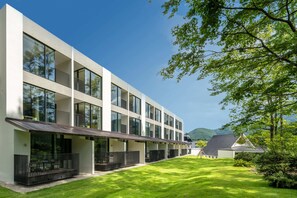 A modern multi-story building with large windows, a flat roof, and a well-maintained lawn. - Holiday Inn Resort Kuroyon by IHG (Omachi)