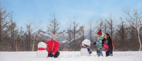 A group of people building snowmen in a snowy outdoor setting.