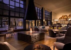 Un área de estar moderna con chimenea, asientos y ventanas amplias.