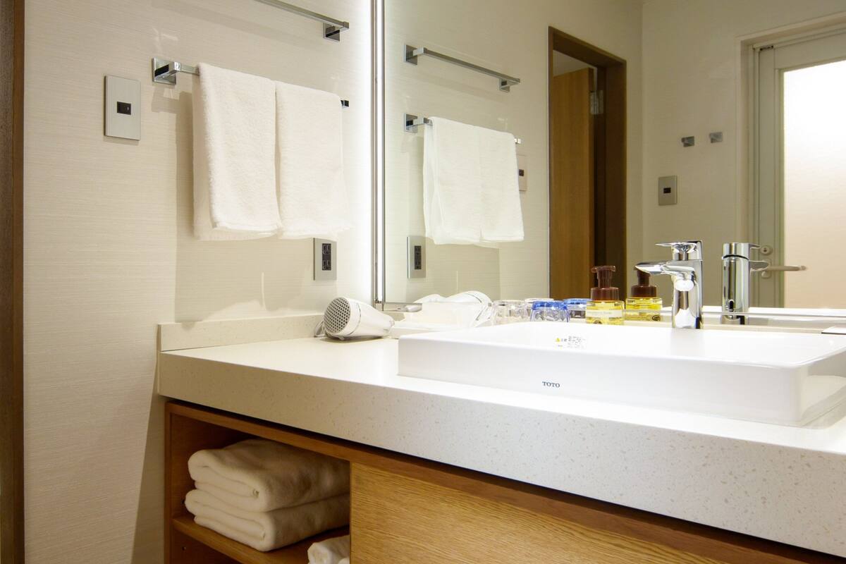 A hotel bathroom with a large mirror, white sink, and a towel rack.