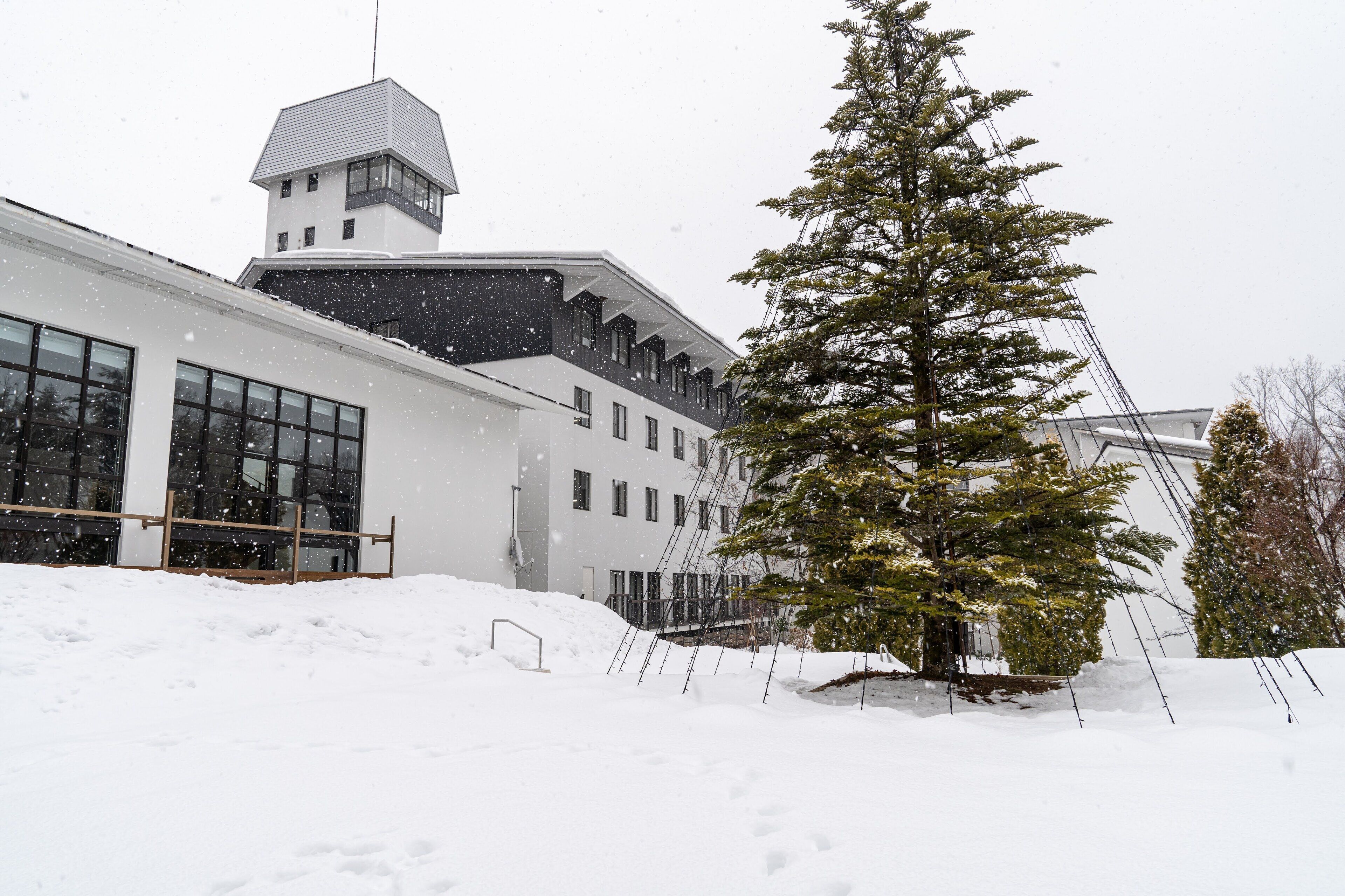 Un edificio con ventanas grandes y una torre, rodeado de nieve.