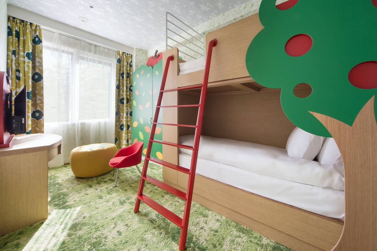 A bunk bed with a ladder, a desk, a chair, and a colorful wall.