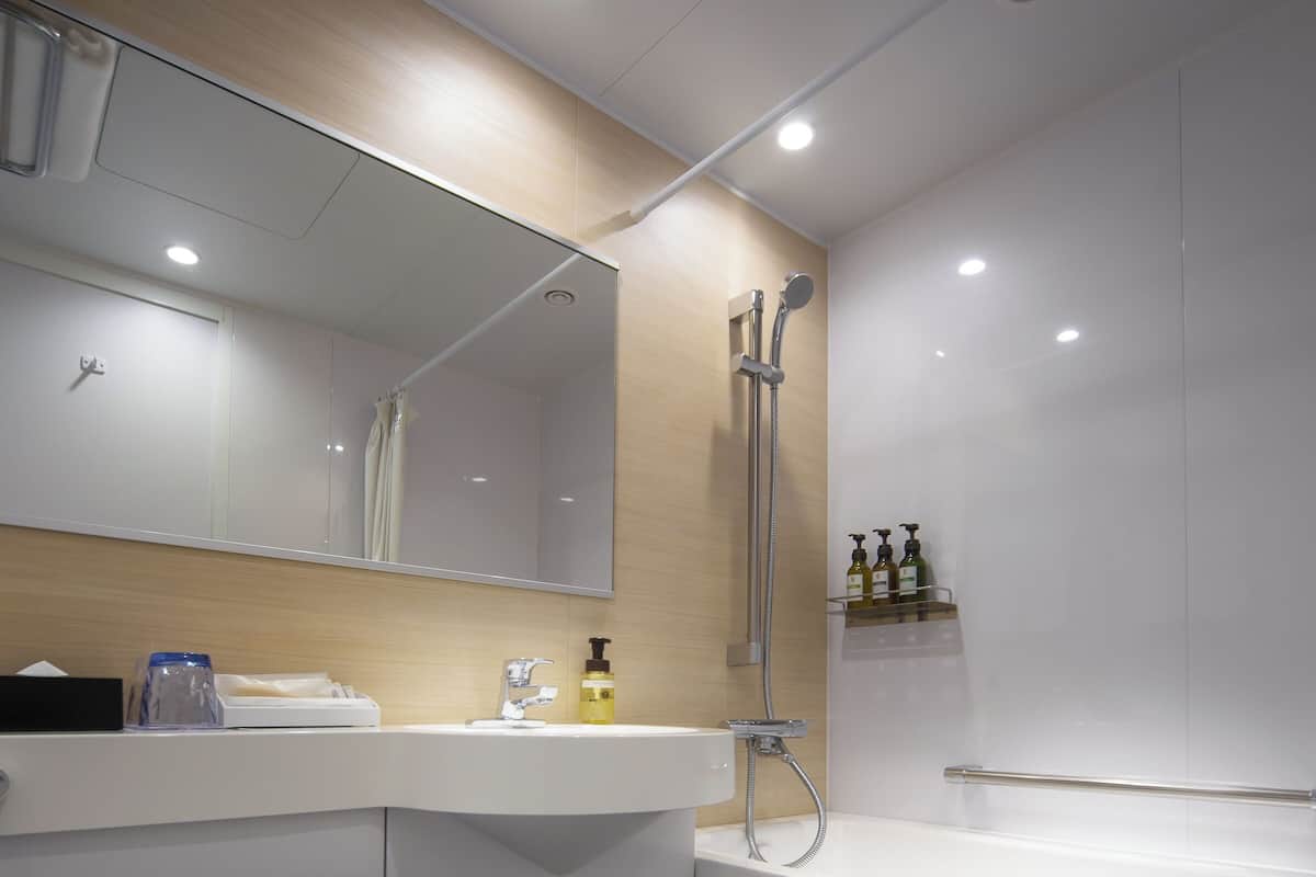 A modern bathroom with a toilet, sink, mirror, shower, and bathtub.