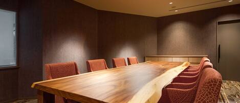 A conference room with a long wooden table and six giraffe-patterned chairs.