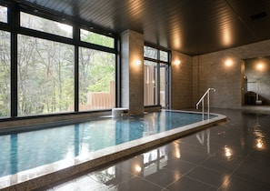 A swimming pool with a stone border, large windows, and a wooden ceiling. - Holiday Inn Resort Kuroyon by IHG (Omachi)