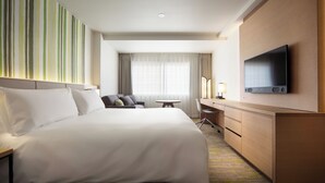 A hotel room with a large bed, a desk, a chair, a television, and a window with curtains. - Holiday Inn Resort Kuroyon by IHG (Omachi)