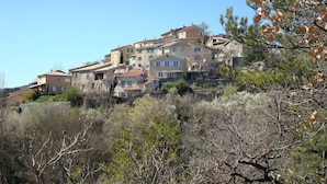 A hillside residential area with multiple buildings, some with balconies and terraces. - Detached 3-star village house overlooking the Durance river. (Thèze)