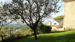 A stone building with a garden and a view of a valley. - Detached 3-star village house overlooking the Durance river. (Thèze)