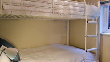 A bunk bed with a pillow and a lamp on the lower bunk.