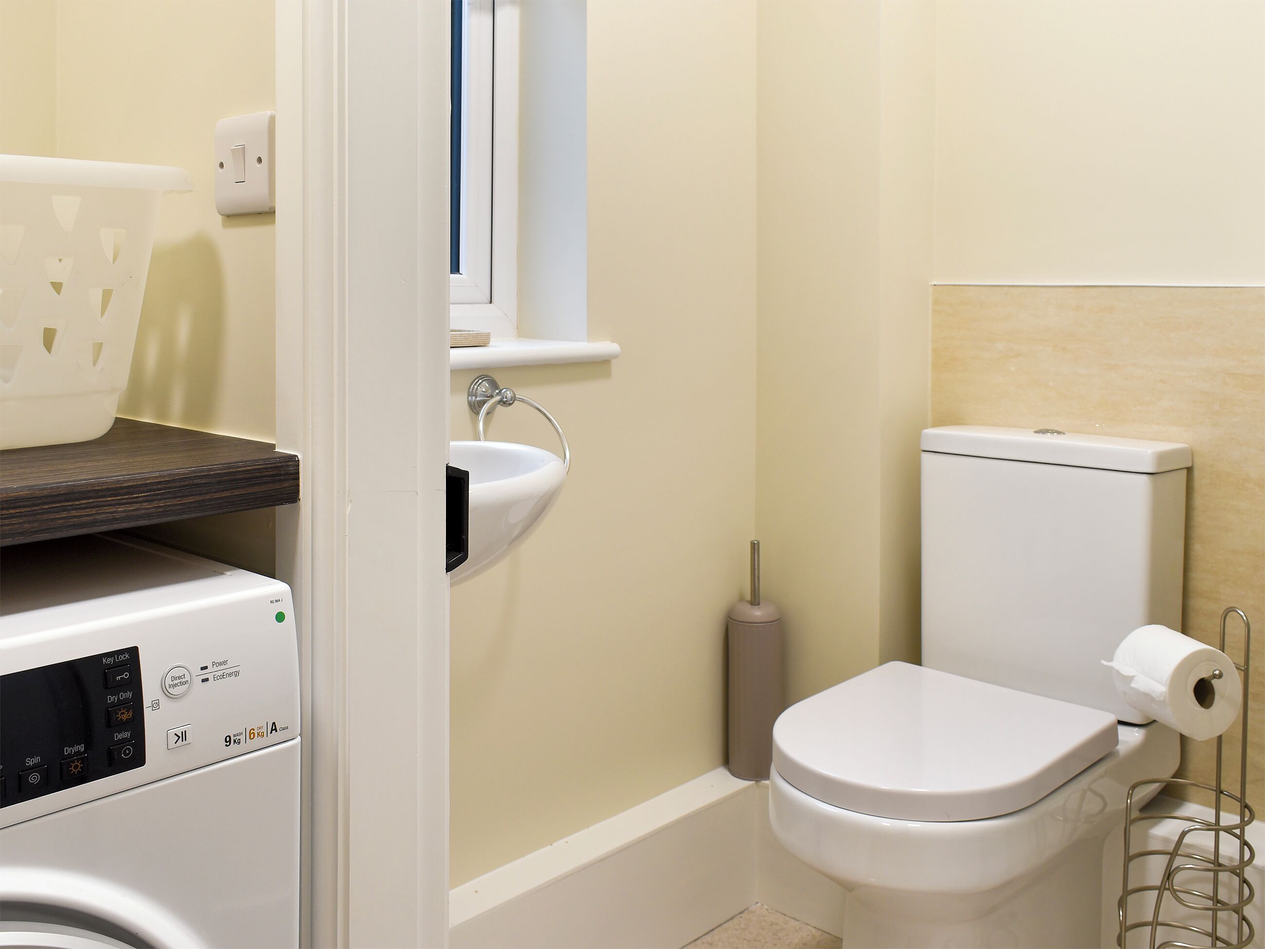 Une petite salle de bain équipée d’un lave-linge, d’un évier et de toilettes.