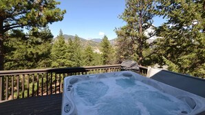 A hot tub on a wooden deck with a view of mountains and trees. - Morning Glory - 3 bedroom home - quiet wooded location (Estes Park)