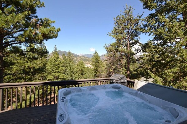 A hot tub on a wooden deck with a view of mountains and trees. - Morning Glory - 3 bedroom home - quiet wooded location (Estes Park)