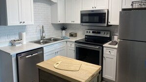 A modern kitchen with white cabinets, stainless steel appliances, and a wooden countertop. - Gulf Shores Plantation Resort by ALBVR (Gulf Shores)