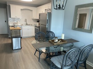 Enjoy meals in this stylish kitchen and dining area, featuring a glass-top table and comfortable seating.