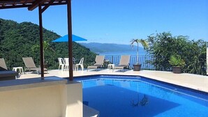 Une piscine dotée de chaises longues et offrant une vue sur un paysage montagneux.