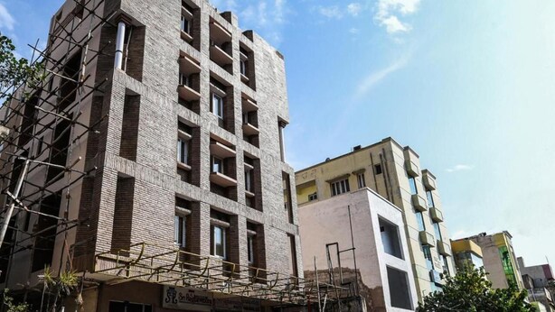 A multi-story building with a modern architectural design, featuring a brick facade and multiple balconies. - Sri Raghavendra Inn (Visakhapatnam)