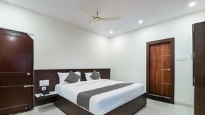 A modern hotel room with a large bed, a ceiling fan, and a wooden wardrobe. - Sri Raghavendra Inn (Visakhapatnam)