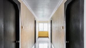 A long, narrow hallway with a polished floor leading to a bright window at the end. - Sri Raghavendra Inn (Visakhapatnam)