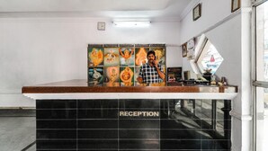A reception area with a black marble counter labeled "RECEPTION" and a wall adorned with religious paintings. - Sri Raghavendra Inn (Visakhapatnam)