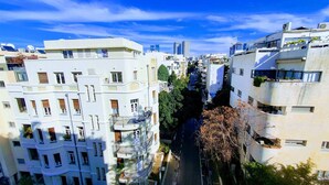 Ein mehrstöckiges Wohngebäude mit Balkonen, eine enge Straße dazwischen und ein strahlend blauer Himmel.