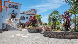 A courtyard with a stone floor, a staircase, and a building with a balcony. - Quinta da Paz Madeira - Studio View Garden 4 (Caniço)