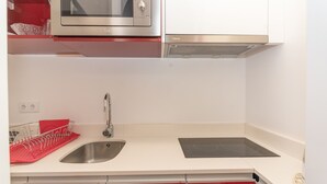 A kitchen with a stainless steel microwave, a sink, and a red dish rack. - Quinta da Paz Madeira - Studio View Garden 4 (Caniço)