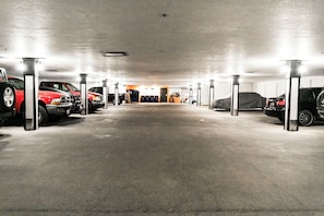 Een parkeergarage met meerdere geparkeerde auto's en een prullenbak in het midden.