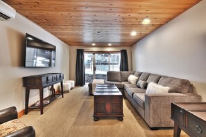 A living room with a wooden ceiling, a large flat-screen TV, a sectional sofa, a coffee table, and a side table. - Top of Main Street - TMI with Parking (Park City)