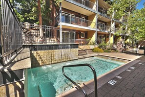 A swimming pool with a metal ladder, surrounded by a brick patio and a multi-story building with balconies. - Top of Main Street - TMI with Parking (Park City)