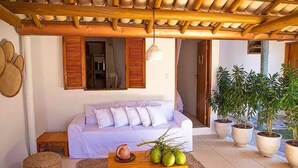 Una habitación acogedora con un sofá blanco, una mesa de centro de madera con cocos, y plantas en macetas.